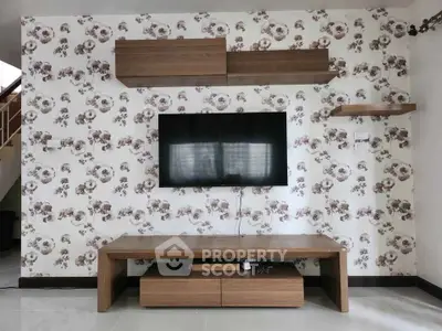 Stylish living room with modern TV setup and floral wallpaper accent wall.