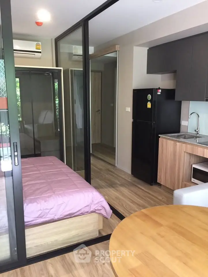 Modern studio apartment with glass partitions and compact kitchen