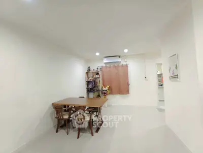 Spacious dining area with wooden table and chairs, bright lighting, and minimalistic decor.