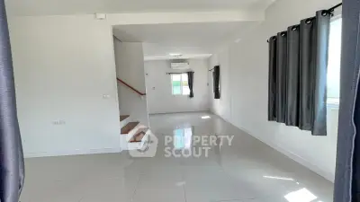 Spacious modern living room with glossy tile flooring and large windows for natural light.