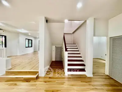 Spacious modern interior with wooden flooring and elegant staircase, perfect for stylish living.