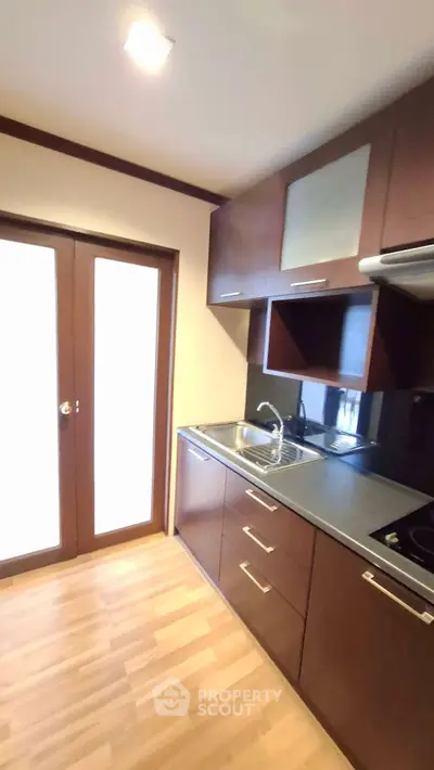 Modern kitchen with sleek cabinetry and wooden flooring, featuring a compact yet functional design.