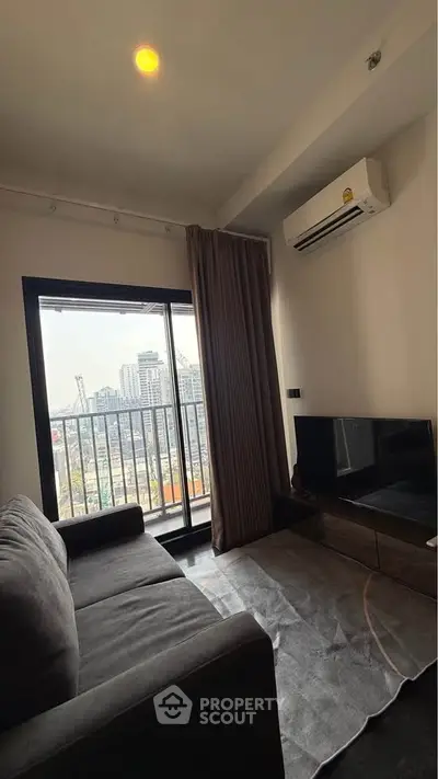 Modern living room with city view, featuring a cozy sofa, TV, and air conditioning.