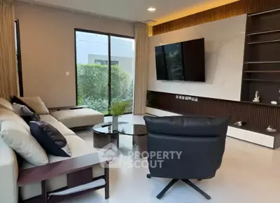 Modern living room with sleek furniture and large TV, featuring a garden view through a glass door.