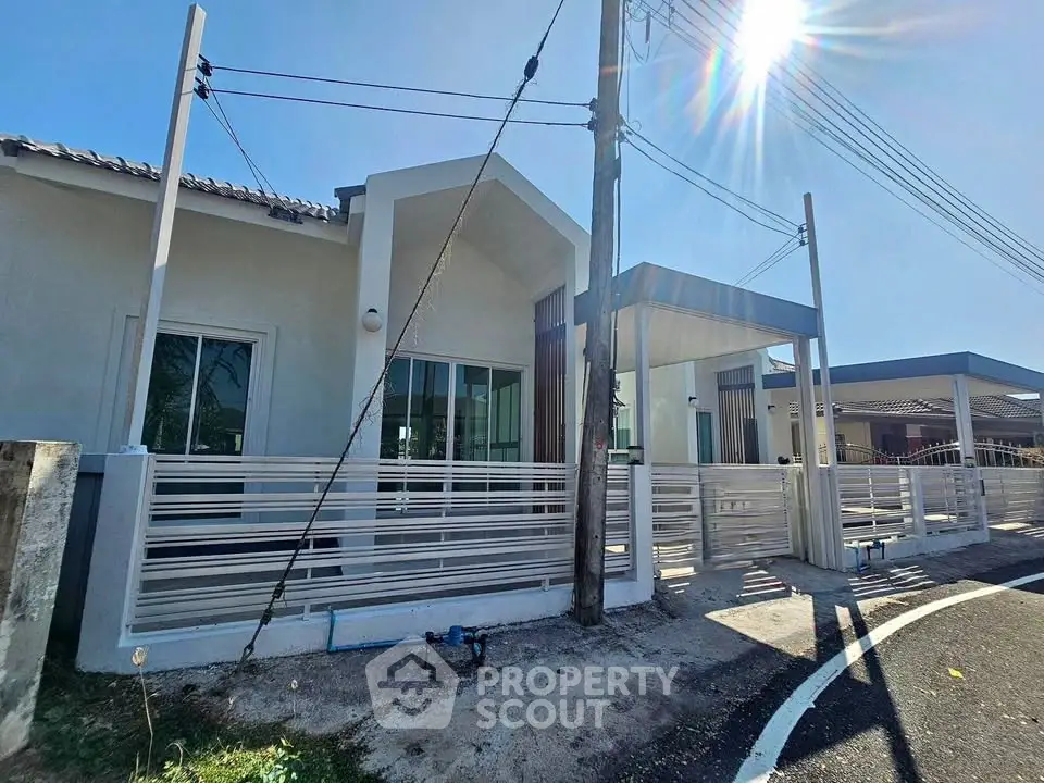 Modern single-story house with sleek fence and driveway under clear blue sky.