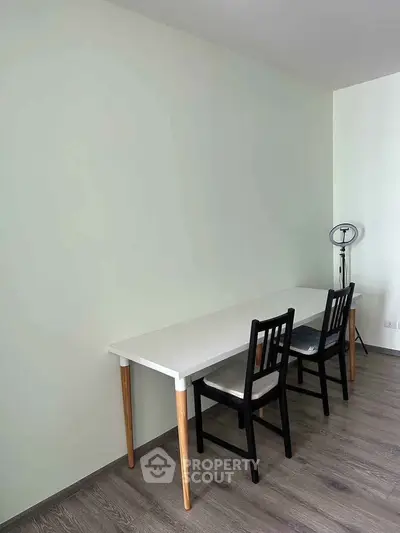 Minimalist study area with white desk and two chairs on wooden floor