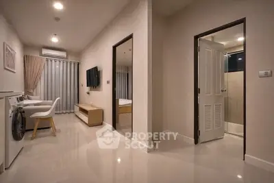 Modern apartment interior with living room, washing machine, and bathroom entrance.