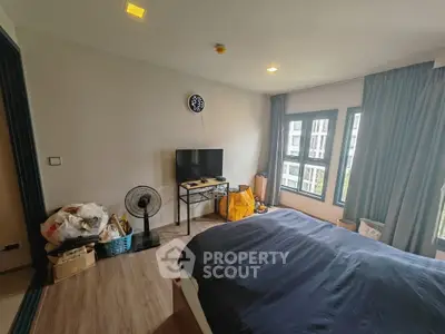 Cozy bedroom with modern decor and large windows offering natural light and city views.