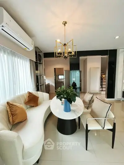 Elegant living room with modern chandelier, curved sofa, and stylish decor in a contemporary home.
