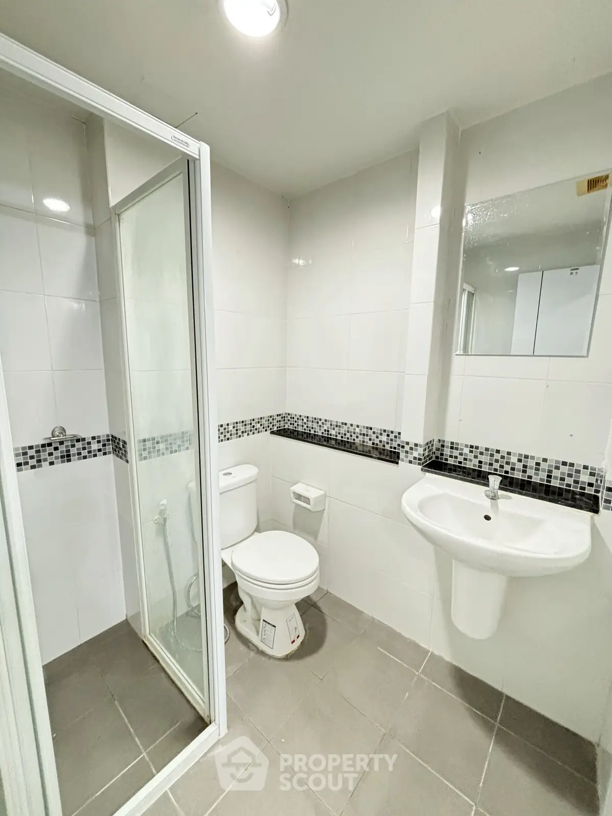 Modern bathroom with shower, toilet, and sink in sleek white and gray design.