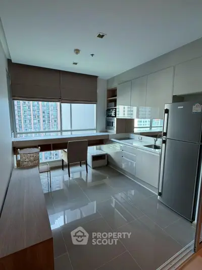 Modern kitchen with sleek cabinetry and large window offering city views, featuring stainless steel appliances.