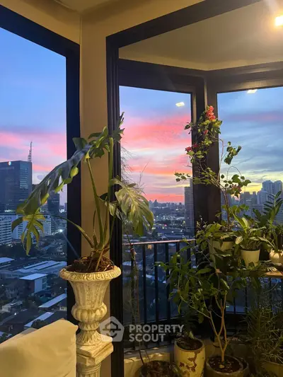 Stunning corner unit with panoramic city view and lush indoor plants at sunset.