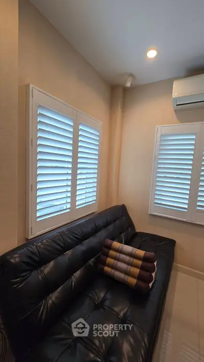 Cozy living room with black leather sofa and modern window shutters