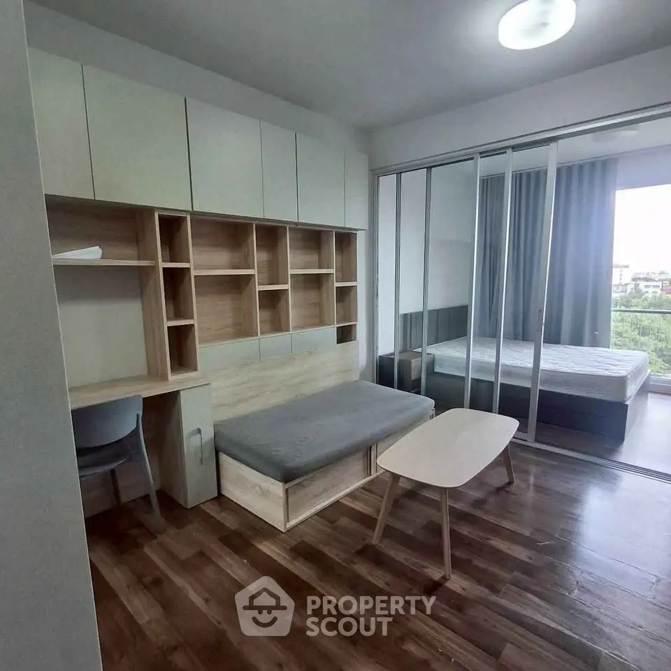 Modern studio apartment with open layout, featuring a cozy living area and bedroom separated by sliding glass doors.