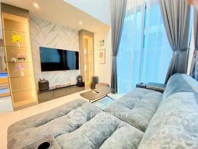 Luxurious modern living room with plush sofa and large TV, perfect for relaxation and entertainment.