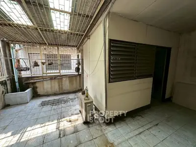 Spacious outdoor area with tiled flooring and natural light, perfect for renovations.