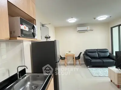 Modern open-plan living room and kitchen with sleek appliances and cozy seating area.