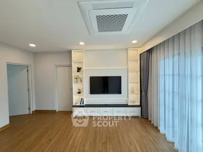 Spacious modern living room with built-in TV unit and elegant curtains