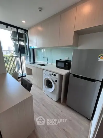 Modern kitchen with sleek appliances and balcony view in a stylish apartment.