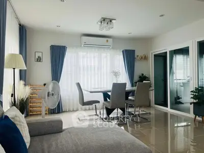 Modern living room with dining area, featuring sleek furniture and large windows for natural light.