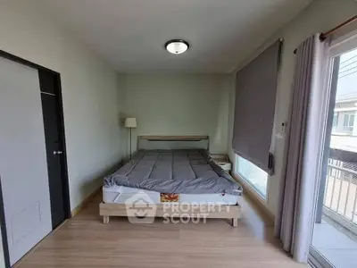 Spacious bedroom with modern decor and large window offering natural light.