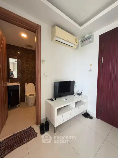 Modern apartment interior with TV and bathroom view, featuring sleek design and air conditioning.