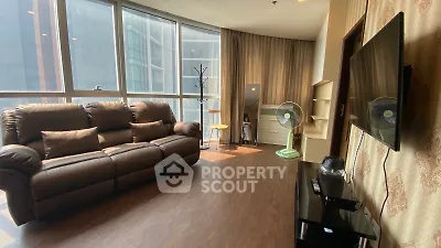 Spacious living room with large windows and modern furnishings in a high-rise apartment.