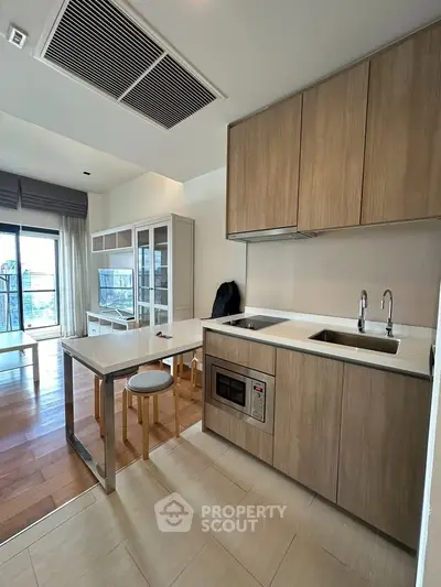 Modern open-layout kitchen with sleek cabinetry and integrated appliances, featuring a bright living area with balcony access.