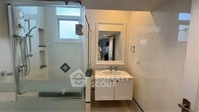 Modern bathroom with glass shower and sleek vanity in a bright setting.