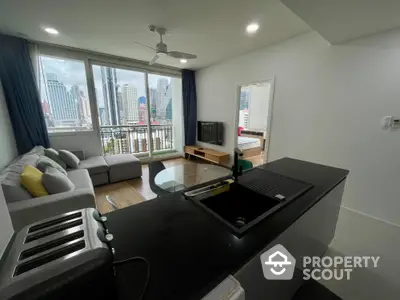 Modern open-plan living room with city view, featuring sleek kitchen and cozy seating area.