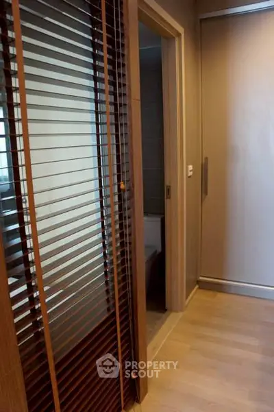 Modern hallway with wooden blinds and sliding door leading to bathroom