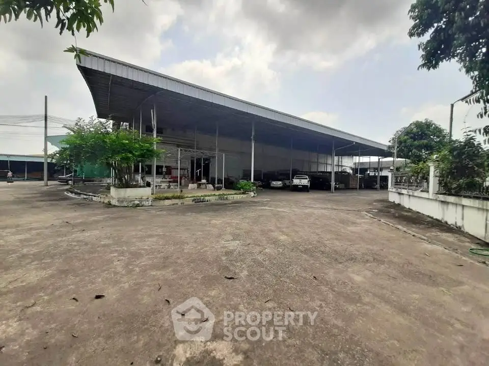 Expansive industrial property with large covered area and ample parking space.