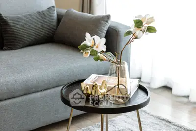 Stylish living room with modern gray sofa and elegant decor on round coffee table.