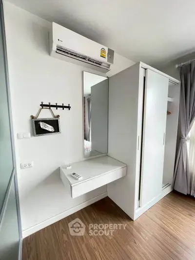 Modern bedroom with sleek white wardrobe and wall-mounted air conditioner, featuring elegant wood flooring.