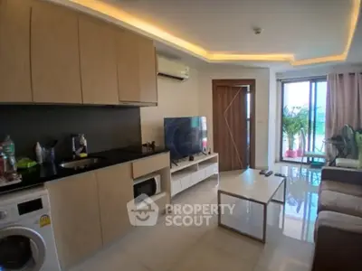 Modern living room with open kitchen, featuring sleek cabinetry and a cozy seating area.