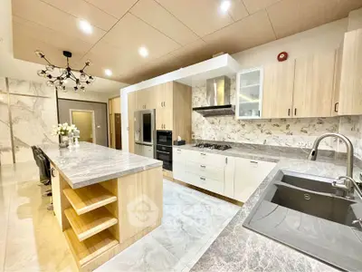 Luxurious modern kitchen with marble countertops and high-end appliances, featuring an open layout and elegant lighting.