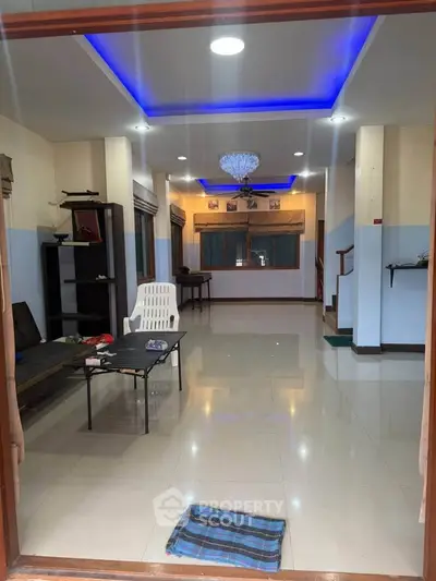 Spacious living room with modern lighting and tiled flooring, perfect for family gatherings.