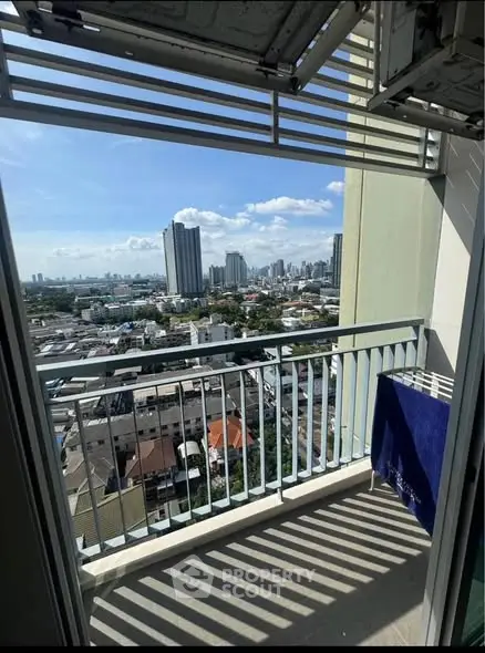 Stunning cityscape view from a high-rise balcony with modern railing and clear blue sky.