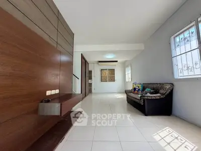 Spacious living room with modern design and ample natural light, featuring a cozy sofa and elegant wall paneling.