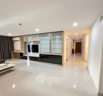 Spacious modern living room with sleek built-in entertainment center and glossy flooring.