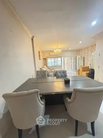 Spacious living room with elegant dining area and chandelier, perfect for entertaining guests.