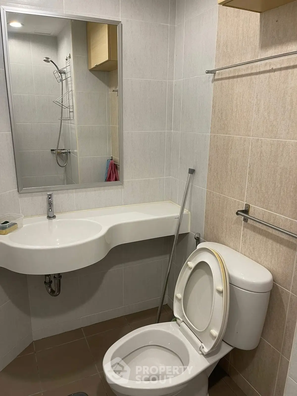 Modern bathroom with sleek fixtures and neutral tiles, featuring a wall-mounted sink and toilet.