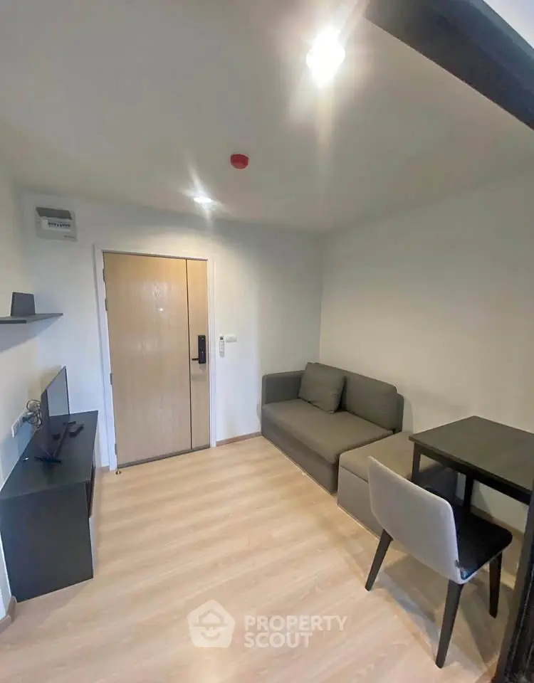 Modern compact living room with sofa, table, and TV in a cozy apartment.