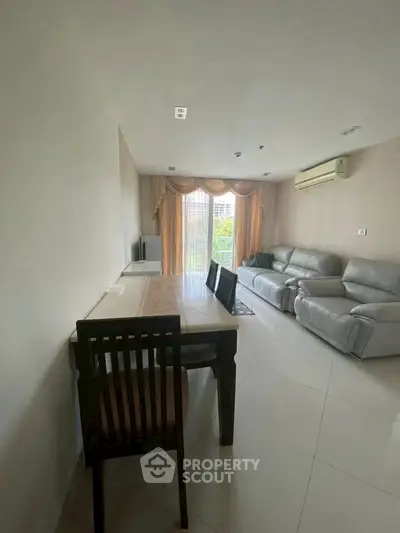 Spacious living room with modern furniture and large window view.