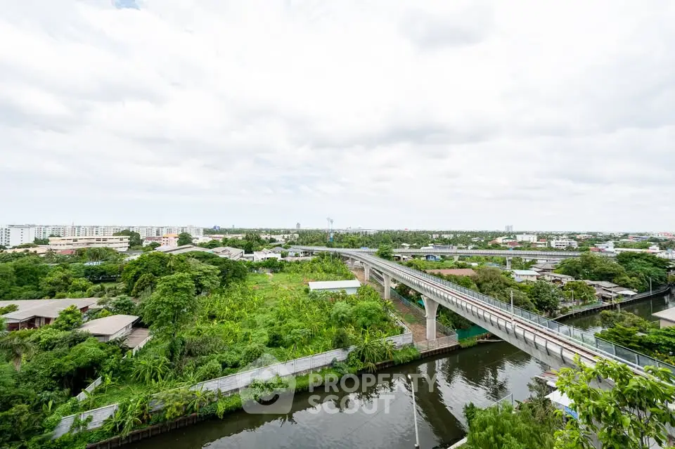 Scenic view of lush greenery and urban landscape with a bridge over a canal.