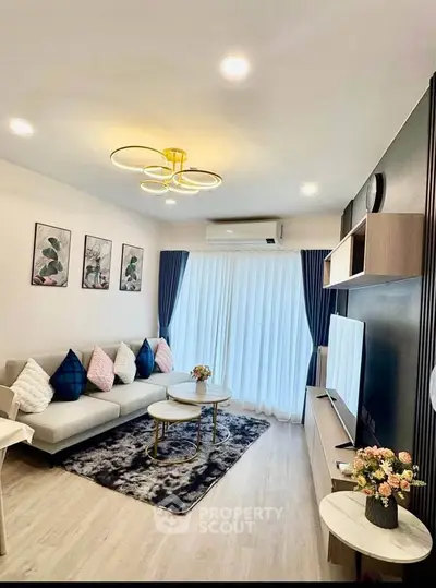 Modern living room with stylish decor, cozy seating, and natural light from large windows.