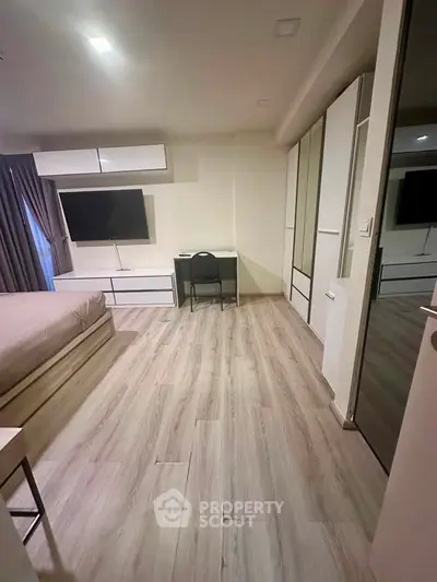 Modern bedroom with sleek furniture and large TV, perfect for urban living.