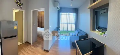 Modern living room with sleek design, featuring a cozy sofa, air conditioning, and a view of the bedroom.