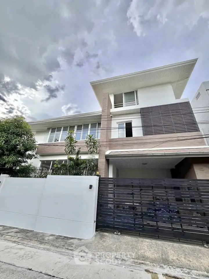 Modern two-story house with sleek design and spacious driveway in a serene neighborhood.
