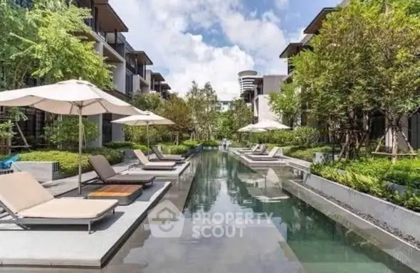 Luxurious residential pool area with sun loungers and lush greenery, perfect for relaxation and leisure.